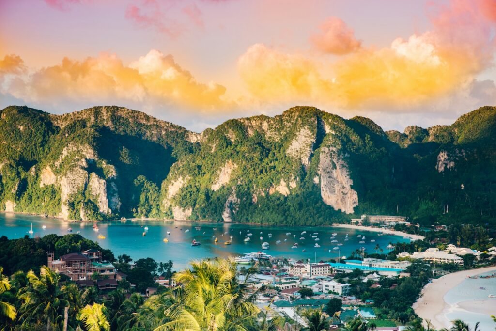 Boats in bay below green mountains at golden hour, Phi Phi Island, Thailand