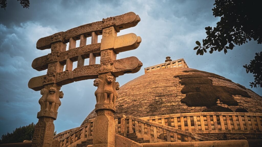 Ancient stone gateway and stupa against cloudy sky, Sanchi, Madhya Pradesh