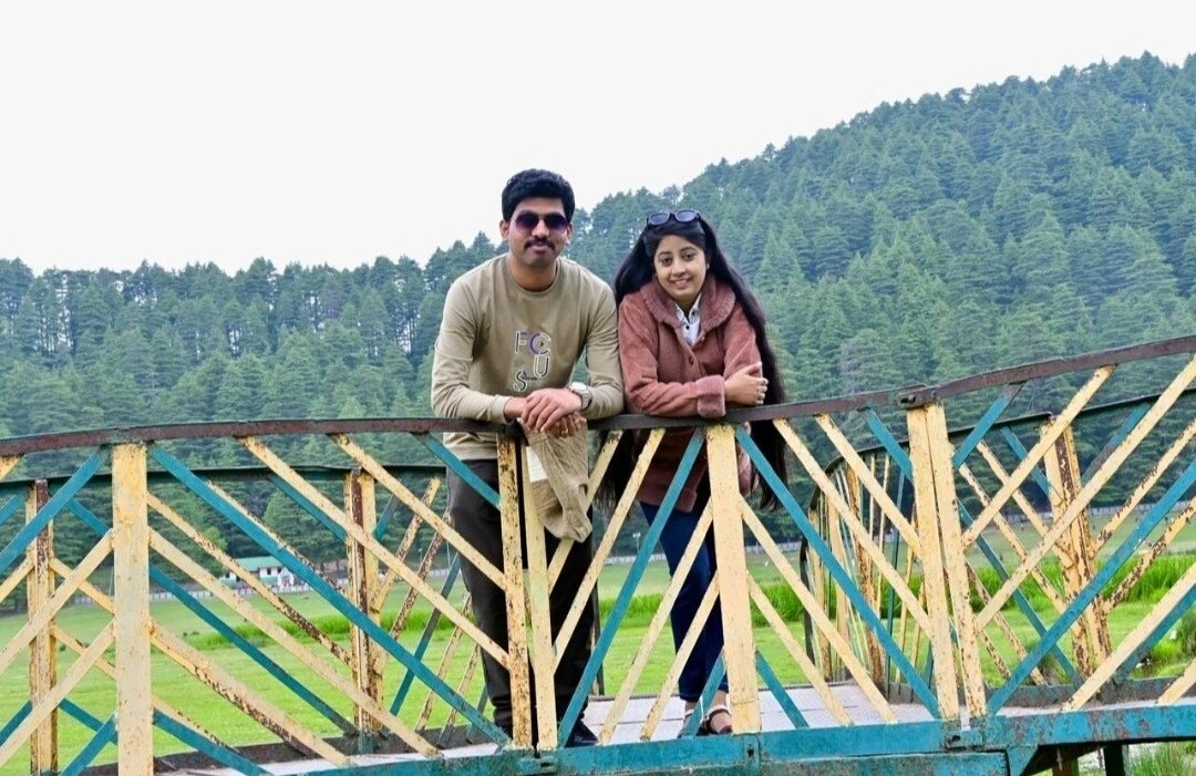 Siona Tours couple on a footbridge with a pine-covered hillside behind